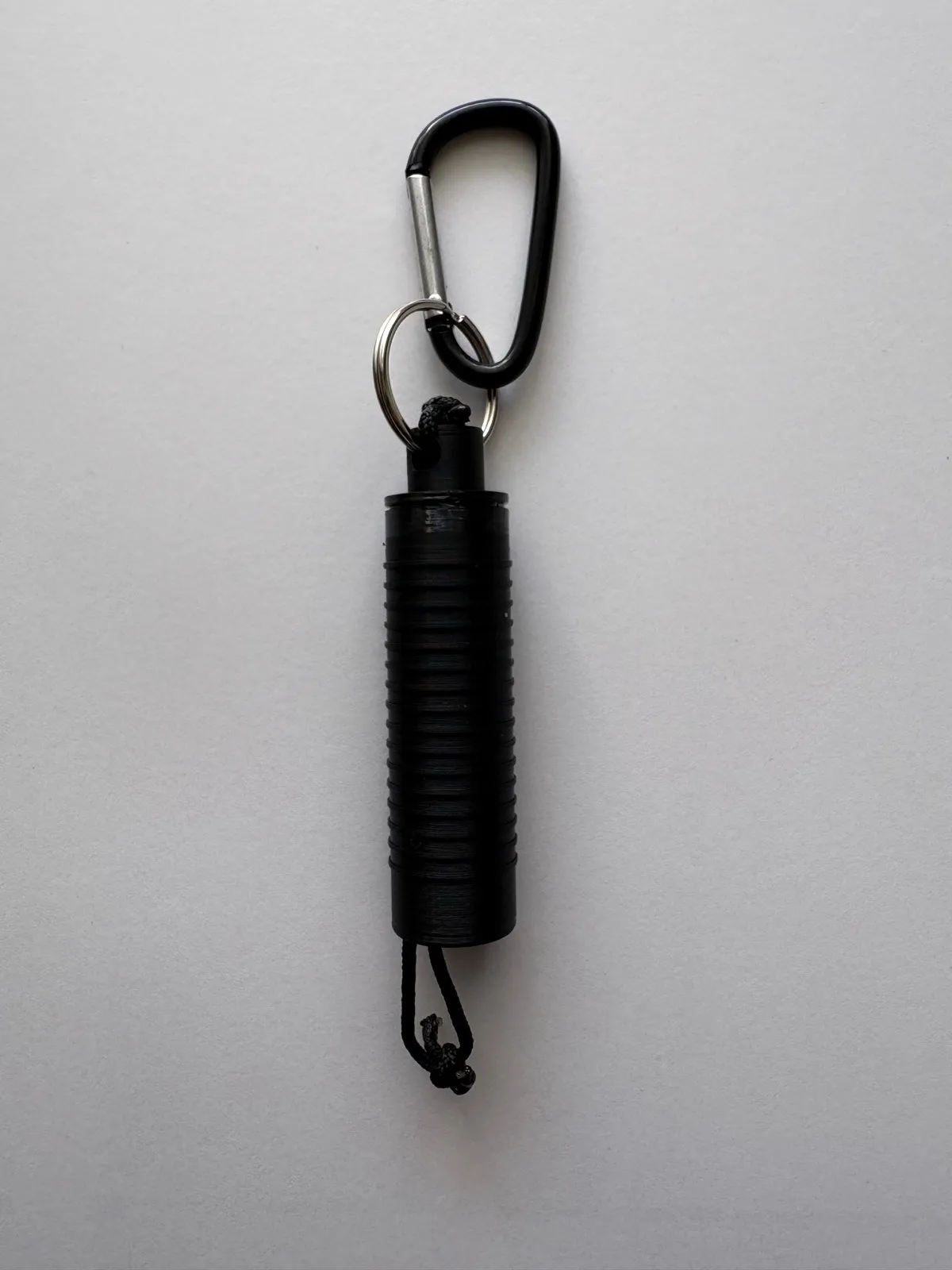 SecuFlag unit in its orange housing with the pull tab exposed, shown with split ring and carabiner